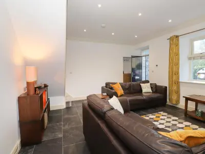 a living room with a leather couch and a television at 1 The Stables in Grange Over Sands