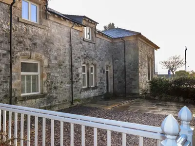 an old stone house with a white fence at 1 The Stables in Grange Over Sands
