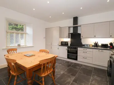 a kitchen with a wooden table with chairs and a stove at 1 The Stables in Grange Over Sands