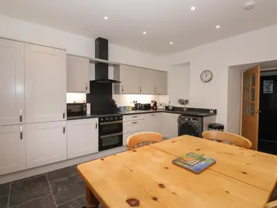 a kitchen with a wooden table and a wooden dining table at 1 The Stables in Grange Over Sands