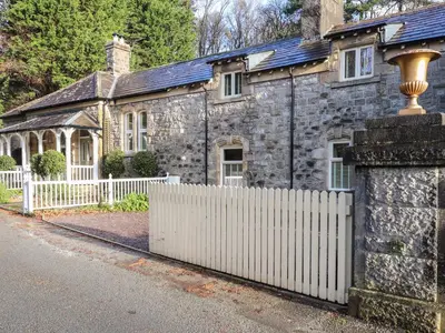 an old stone house with a white fence at 1 The Stables in Grange Over Sands