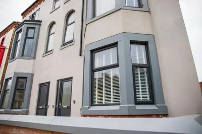 a house with black windows and white shutters at Withnell Stays - Apartment One - Ground Floor - Retro Gaming Machine in Blackpool