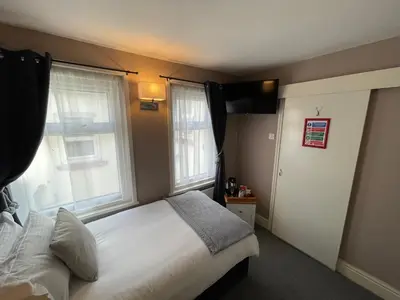 a bedroom with a white bed and two windows at McGraths Hotel & Public Bar in Blackpool