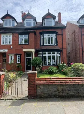 a red brick house with a gate in front of it at Entire Seaside Home, Sleeps 8, All en-suite rooms in New Brighton