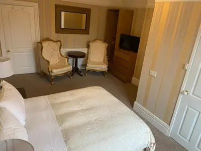 a bedroom with a bed and two chairs and a television at Entire Seaside Home, Sleeps 8, All en-suite rooms in New Brighton