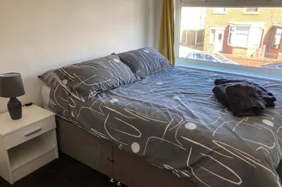 a bed with a blue comforter and a window at House - Sleeps 5 - Pet friendly - Garden - Parking in Saint Annes on the Sea