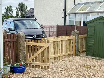 a wooden fence with a van parked in a driveway at Hornby Cottage in Saint Michaels on Wyre