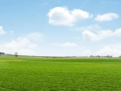 a green field with a blue sky and clouds at Hornby Cottage in Saint Michaels on Wyre