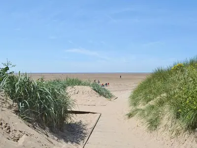 a group of people walking on a sandy beach at Excalibur Cottage in Saint Annes on the Sea