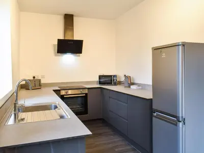 a kitchen with a stainless steel refrigerator and a sink at Excalibur Cottage in Saint Annes on the Sea