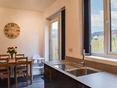 a kitchen with a sink and a dining room with a table at Excalibur Cottage in Saint Annes on the Sea