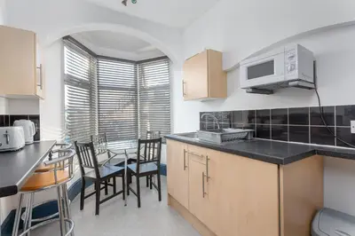 a kitchen with a counter and some chairs and a table at Blackpool Lodge Apartments in Blackpool