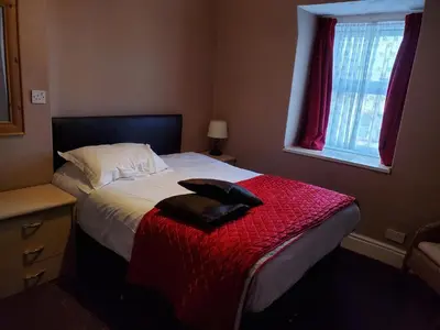 a bedroom with a bed with a red blanket and a window at the cumbrian hotel in Blackpool