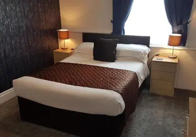 a hotel room with a large bed with two lamps at the cumbrian hotel in Blackpool