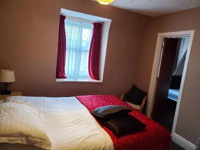 a bedroom with a bed with a red blanket and a window at the cumbrian hotel in Blackpool