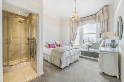 a bedroom with a shower and a bed with pink pillows at Pier View House in Blackpool