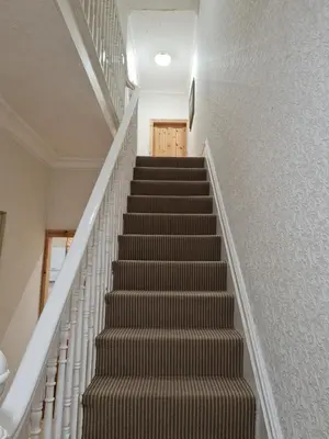 a staircase in a home with white walls andbrown carpet at Cheerful 4-bedroom holiday home close to the Sea in Blackpool