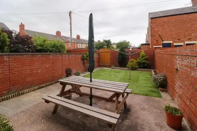 a wooden picnic table in a garden with a fence at Cheerful 4-bedroom holiday home close to the Sea in Blackpool