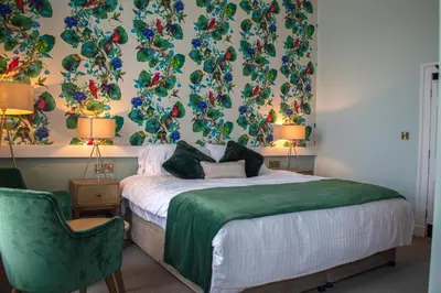a bedroom with a bed and a green chair at The Clock Face Prescot in Prescot