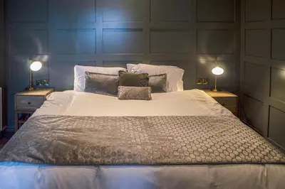 a bedroom with a large bed with two lamps at The Clock Face Prescot in Prescot