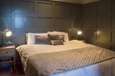 a bedroom with a large bed with two lamps at The Clock Face Prescot in Prescot