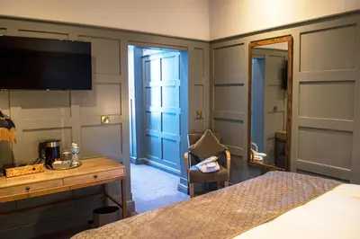 a bedroom with a bed and a desk and a mirror at The Clock Face Prescot in Prescot