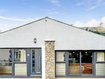 a white building with large windows and a roof at Woodgate Cottage in Dalton in Furness
