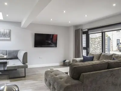 a living room with a couch and a tv on the wall at Woodgate Cottage in Dalton in Furness