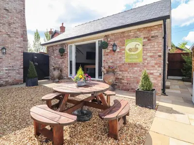 a patio with a wooden table and two benches at Moor End Manor in Poulton le Fylde