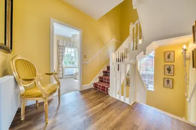 a hallway with yellow walls and a chair and stairs at Moor End Manor in Poulton le Fylde