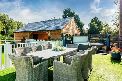 a patio with a table and chairs and a dog house at Moor End Manor in Poulton le Fylde