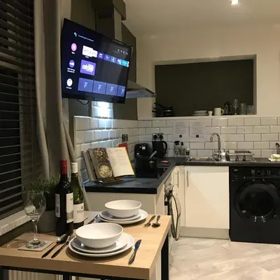 a kitchen with a table with plates and a tv at Contemporary 1 bed studio for comfy stay in Wigan in Wigan