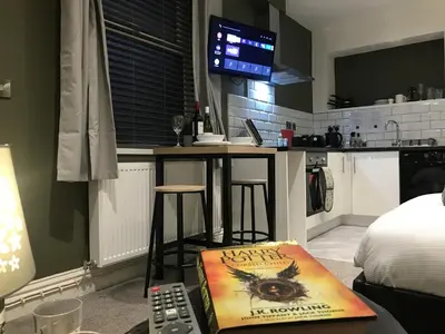 a room with a kitchen with a bar and a television at Contemporary 1 bed studio for comfy stay in Wigan in Wigan