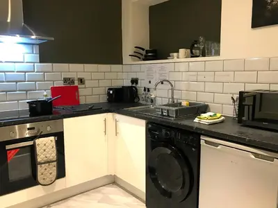 a kitchen with a sink and a washing machine at Contemporary 1 bed studio for comfy stay in Wigan in Wigan