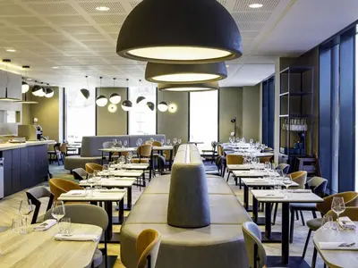 a restaurant with tables and chairs and a large light fixture at Novotel Liverpool Paddington Village in Liverpool
