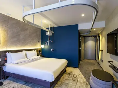 a bedroom with a large bed and a blue wall at Novotel Liverpool Paddington Village in Liverpool
