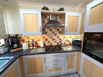 a kitchen with white cabinets and black counter tops at Apartment 1 in Morecambe