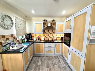 a kitchen with wooden cabinets and a clock on the wall at Apartment 1 in Morecambe