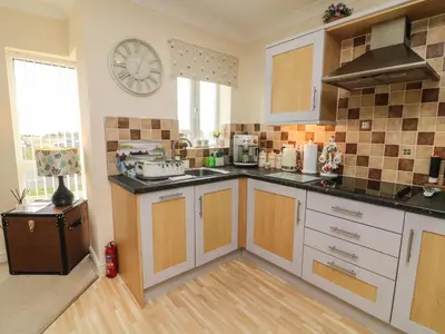 a kitchen with white cabinets and a clock on the wall at Apartment 1 in Morecambe
