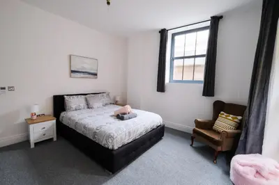 a bedroom with a bed and a chair and a window at The Eden Warehouse - Pink Apartment (sleeps 4) in Southport