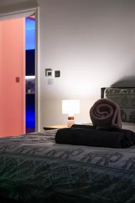 a bedroom with a bed with a rolled up blanket at The Eden Warehouse - Pink Apartment (sleeps 4) in Southport