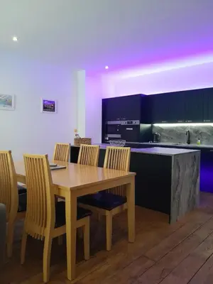 a kitchen with a wooden table and some chairs at The Eden Warehouse - Pink Apartment (sleeps 4) in Southport