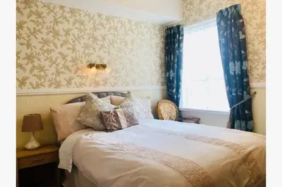 a bedroom with a bed with blue curtains and a window at Dunromin Hotel in Blackpool