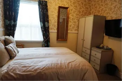 a bedroom with a bed and a dresser and a window at Dunromin Hotel in Blackpool