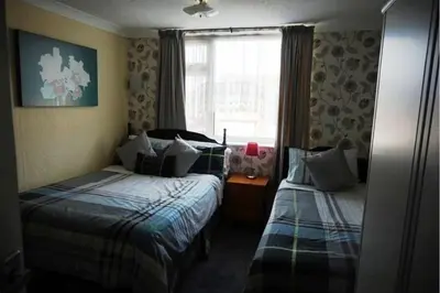 a small bedroom with two beds and a window at Dunromin Hotel in Blackpool
