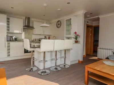 a kitchen with white cabinets and a table and chairs at 2 Bedroom Annexe in Morecambe