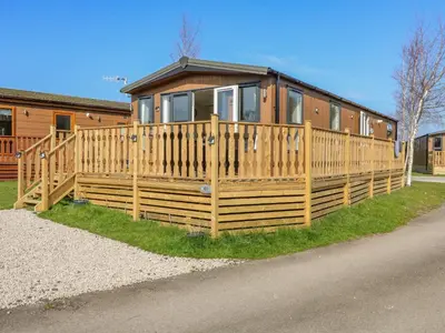a house with a wooden fence in front of it at Birch Lodge in Carnforth