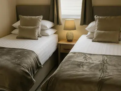a bedroom with two beds and a lamp on a table at Birch Lodge in Carnforth