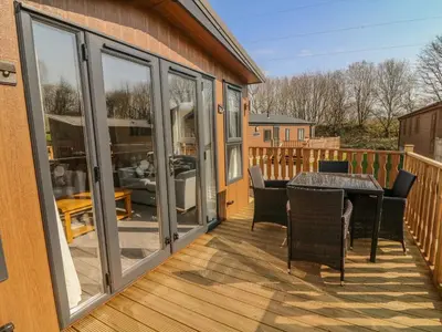 a screened porch with a table and chairs on a deck at Birch Lodge in Carnforth