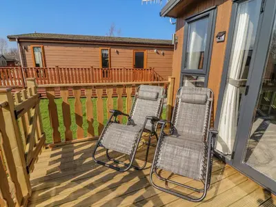 a couple of chairs sitting on a deck at Birch Lodge in Carnforth